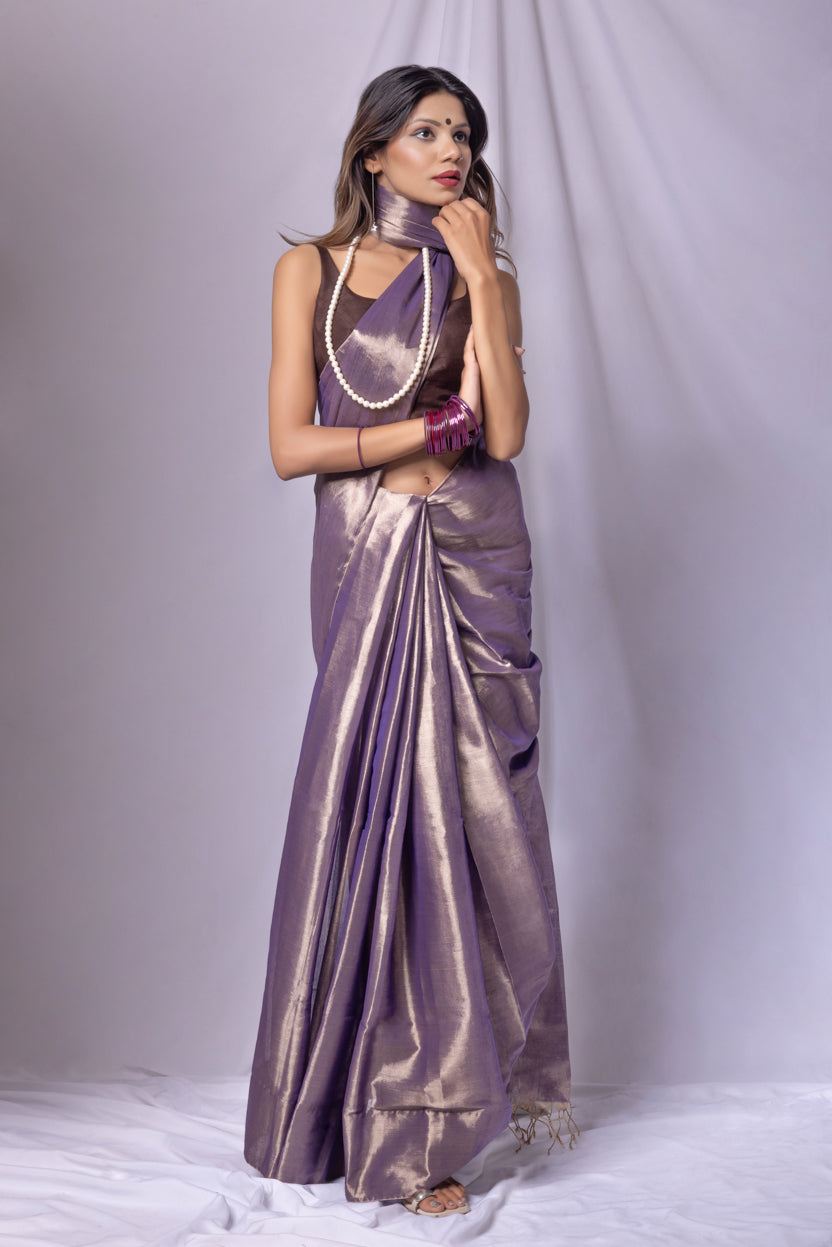 Woman wearing a purple saree with a matching blouse against a white background