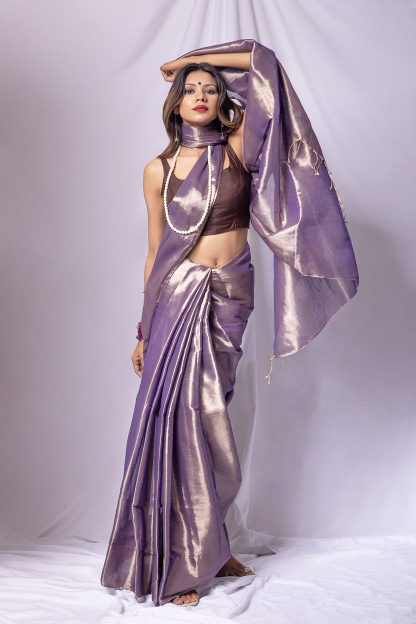 Woman in a purple saree with a matching blouse against a white background