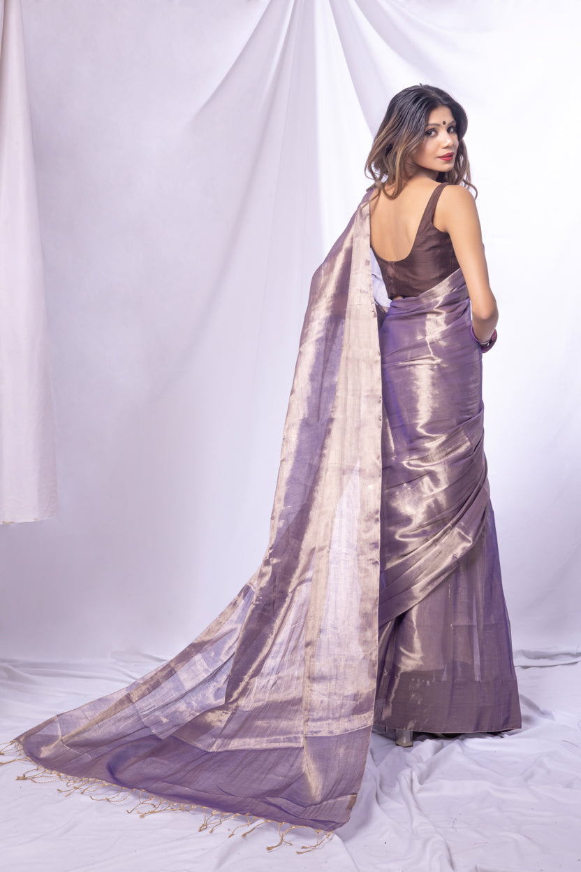 Woman wearing a long, flowing purple saree with a white background