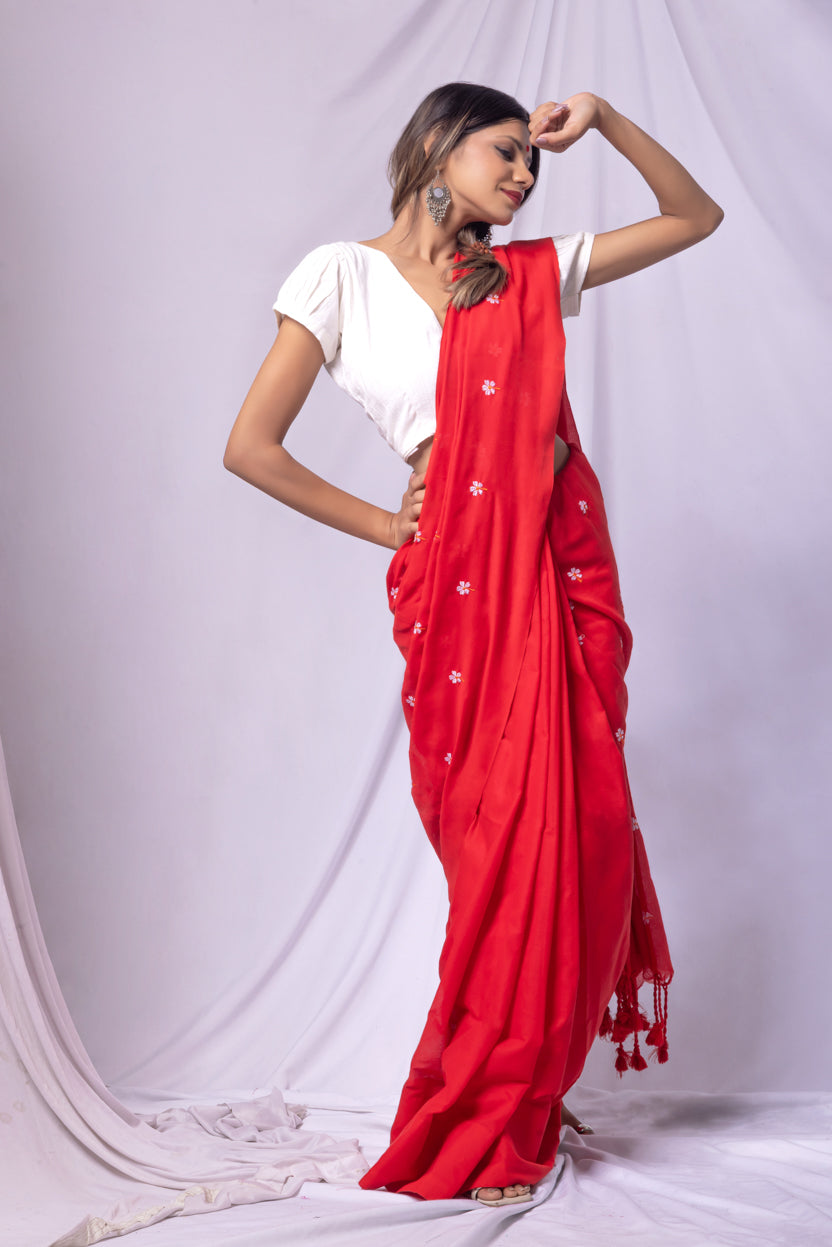 Woman wearing a red saree with white patterns on a white background