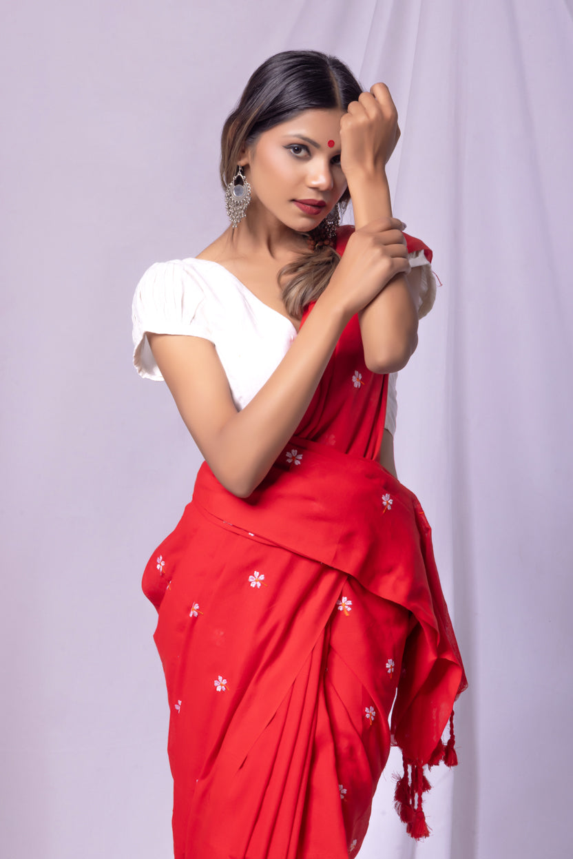Woman wearing a red saree with white patterns on a light purple background