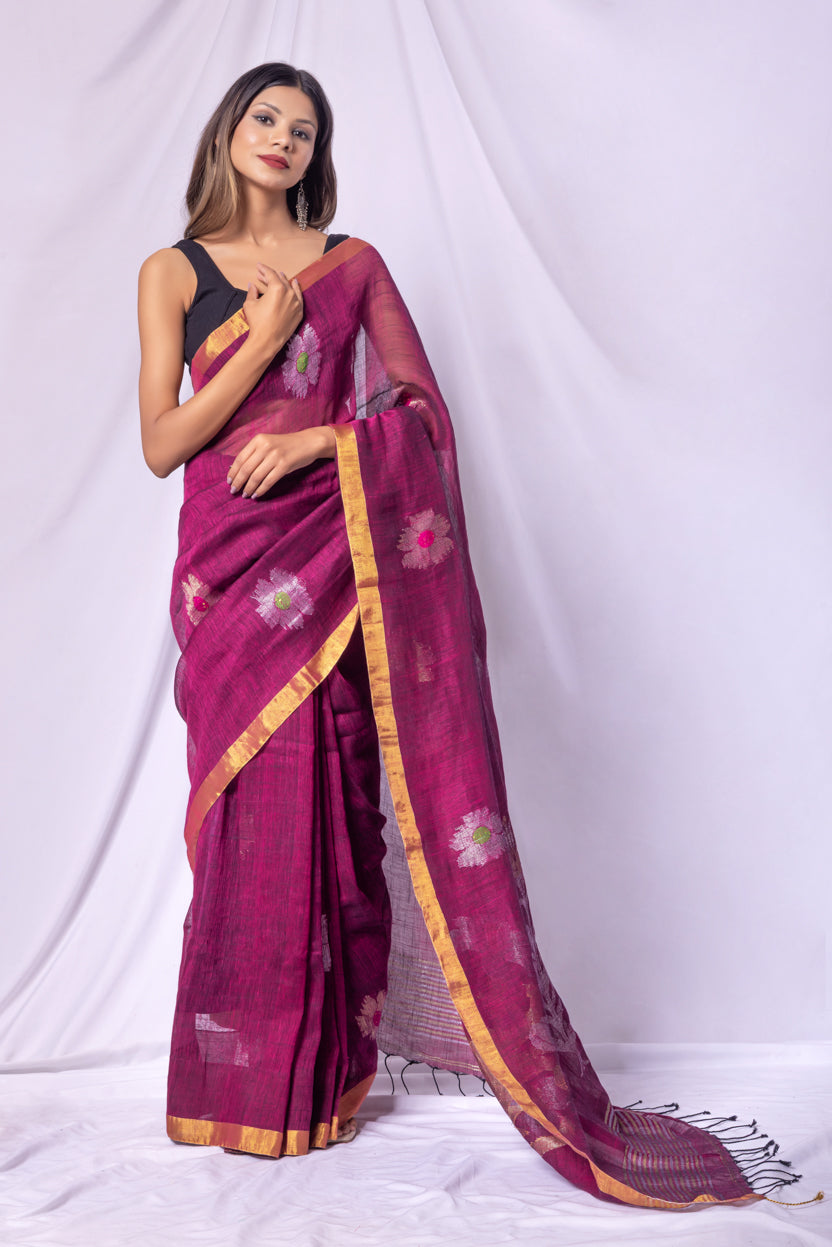Woman wearing a magenta saree with gold border on a white background