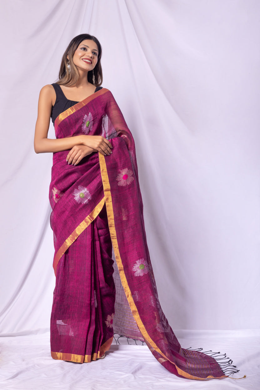 Woman wearing a magenta saree with floral patterns on a white background