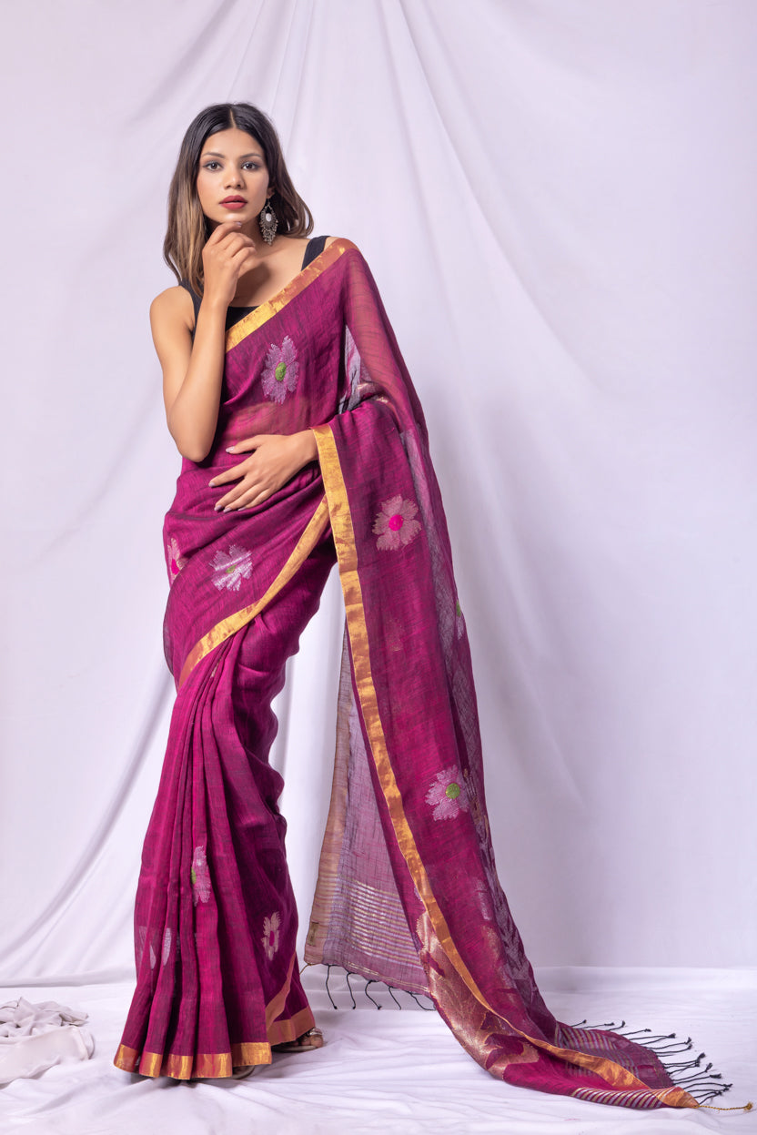 Woman wearing a magenta saree with floral patterns on a white background