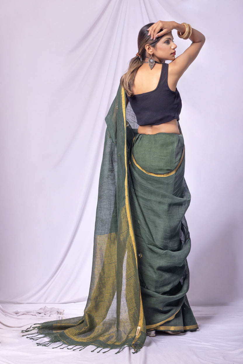 Woman wearing a green saree with a black blouse against a white background