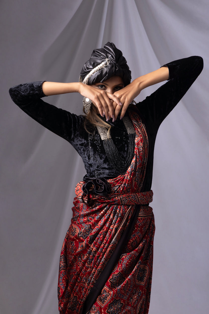 Person wearing a black top and red patterned skirt against a gray background