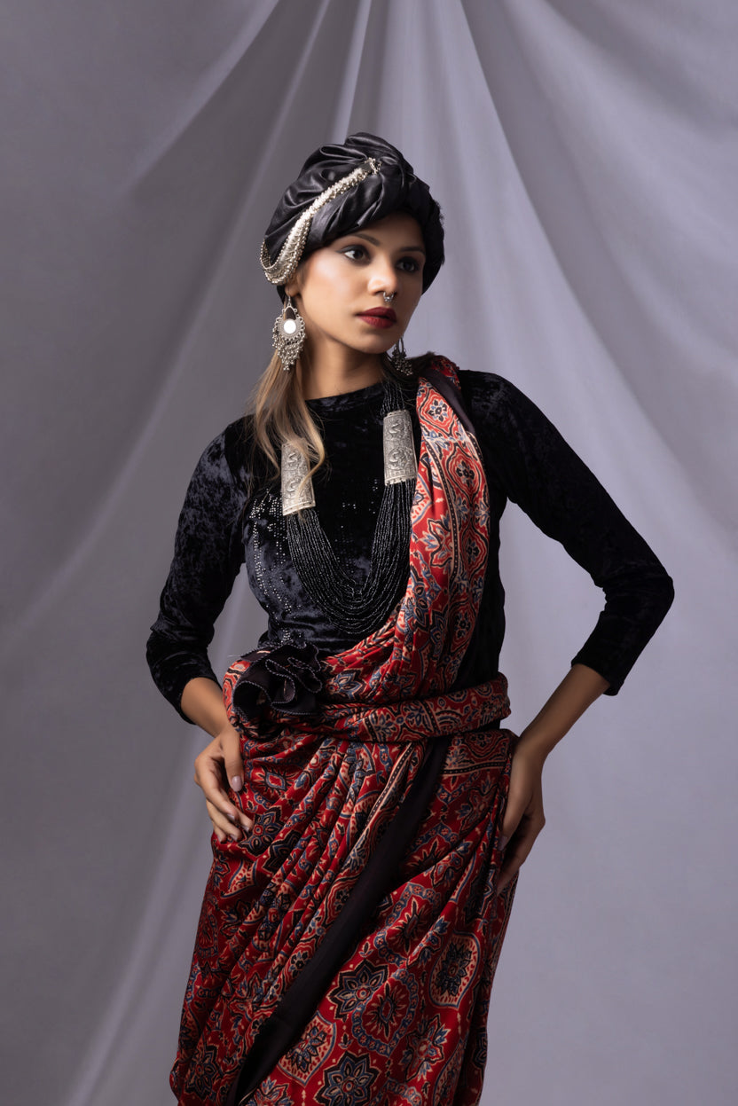 Woman wearing a black top and red patterned skirt with a gray background