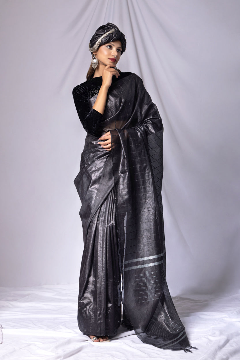 Woman wearing a black saree with a white border on a white background