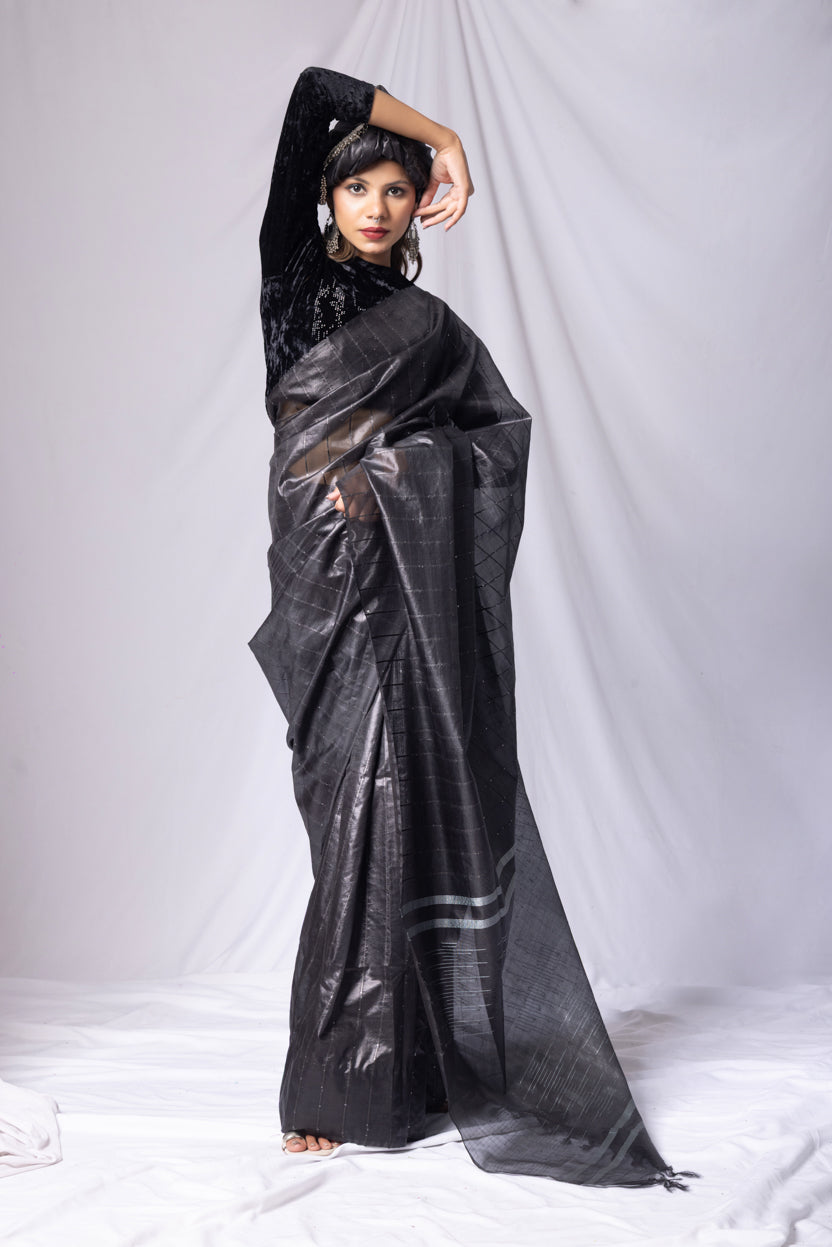 Woman wearing a black outfit with a large black and gray scarf against a white background