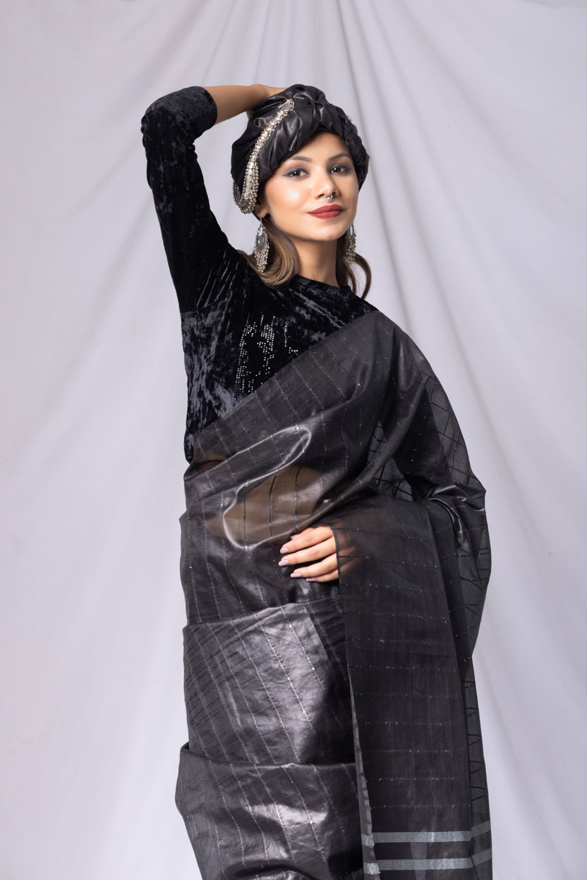 Woman wearing a black outfit with a large black and gray scarf against a white background