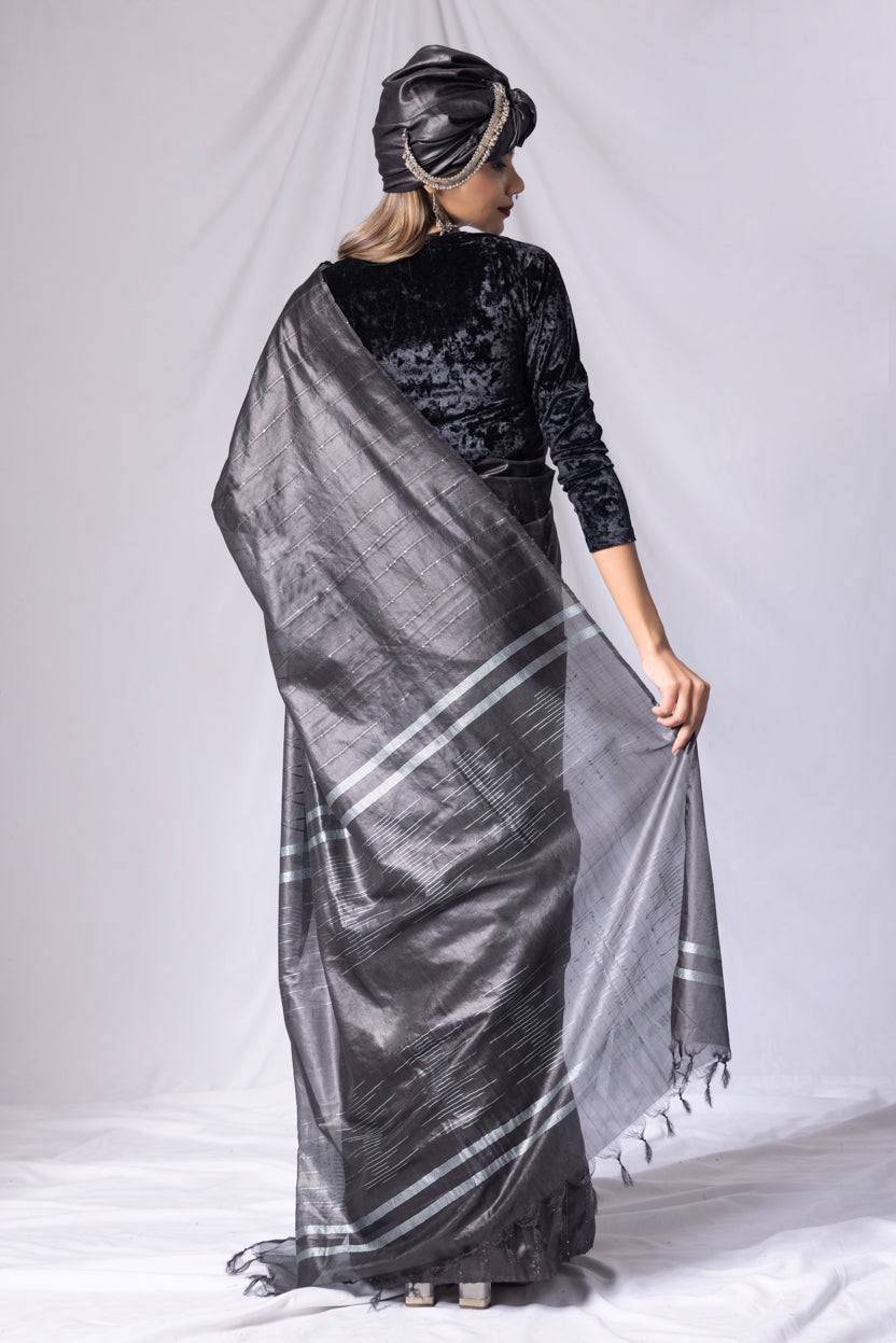 Woman wearing a black saree with white patterns on a white background